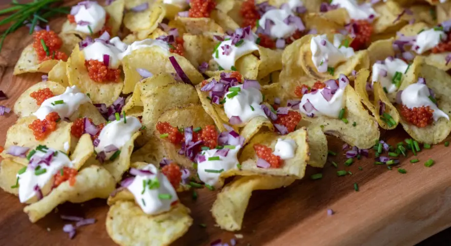 Krispiga chips med klickar av smetana, röd rom, finhackad rödlök och gräslök. En festlig förrätt!