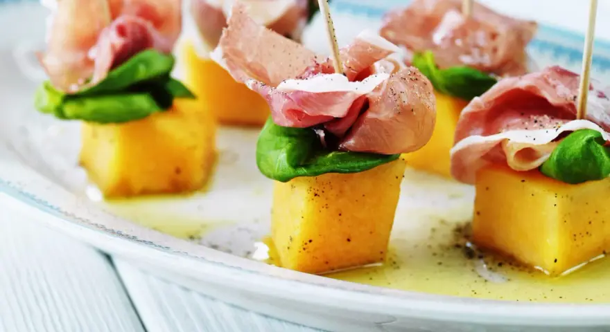Små spett med saftig melon och salt skinka, toppade med färsk basilika. En klassisk och läcker kombination av melon och skinka.