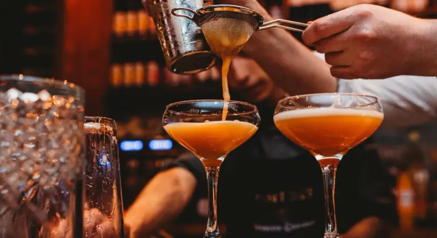 En bartender häller upp en Pornstar Martini i ett elegant glas.