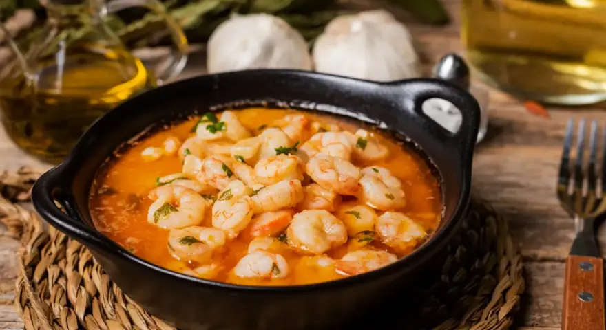 En skål med saftiga gambas pil pil i en het oljeblandning, med vitlök och persilja. En klassisk spansk rätt som värmer själen.