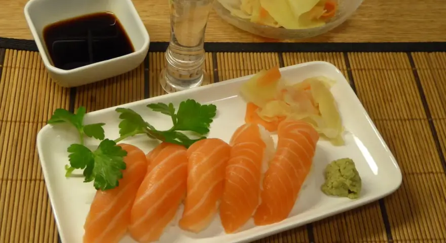 Njut av grillad lax sushi med wasabi, ingefära, sojasås och en shot sake.