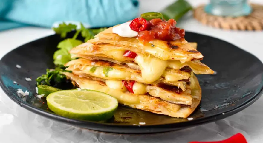 En stapel krispiga quesadillas med smält ost, jalapeños och salsa. Ett perfekt monterey jack ost alternativ för en smakrik måltid.