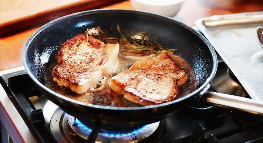 Två saftiga fläskkotletter steks i en panna med rosmarin. Ett perfekt karre recept för en god middag.