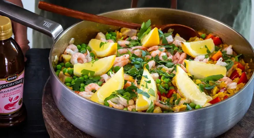 En härlig paella med räkor, ärtor och citronklyftor, perfekt för ett gott paella recept.