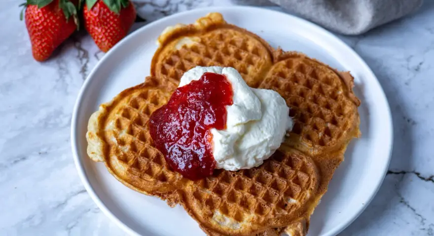 Gyllene belgiska våfflor med vispad grädde och jordgubbssylt. Ett perfekt recept för en lyxig frukost eller fika.