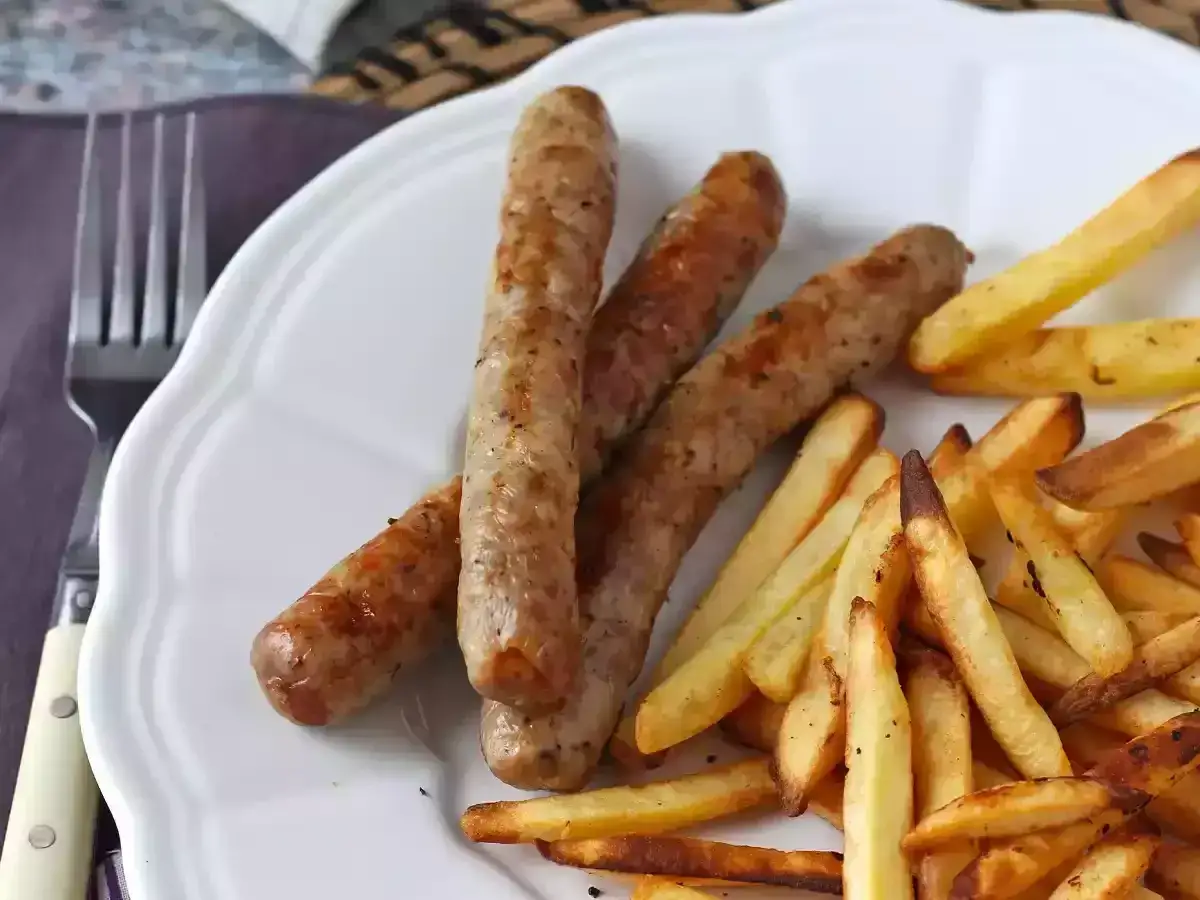 Saftig korv i airfryer med krispiga pommes frites p&aring; en vit tallrik. Enkel och god middag.
