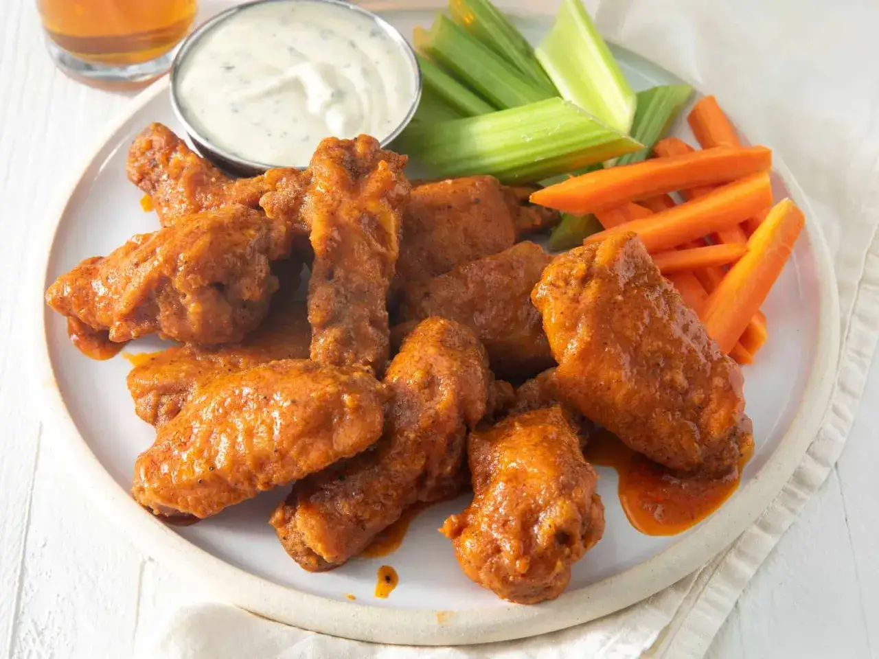 En tallrik med saftiga buffalo wings, serverade med krispiga morots- och selleristavar samt en skål med dippsås.