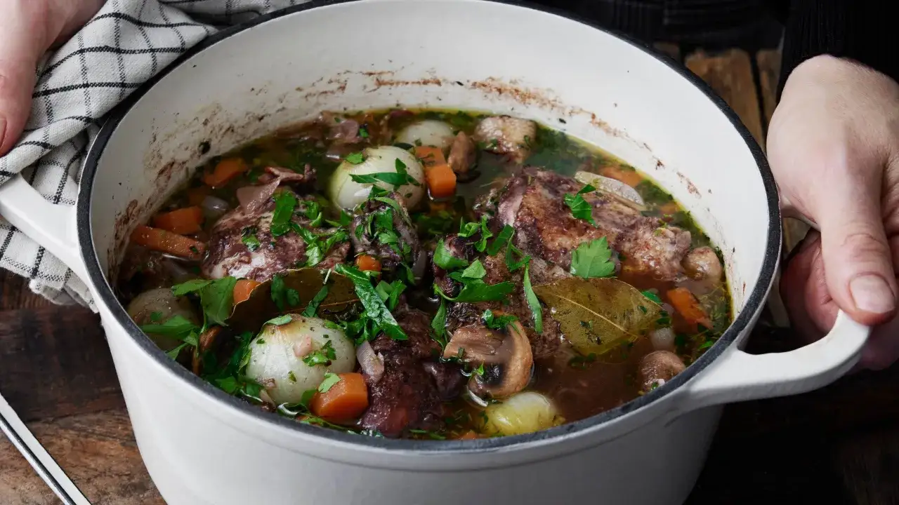 En mustig gryta med kyckling, champinjoner, l&ouml;k och mor&ouml;tter i en djup r&ouml;dvinss&aring;s. En klassisk coq au vin som doftar underbart.