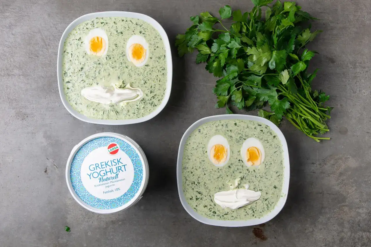 Tv&aring; sk&aring;lar med gr&ouml;n, &ouml;rtig varm mat dekorerad som ansikten med &auml;gg och grekisk yoghurt. En burk grekisk yoghurt st&aring;r bredvid.