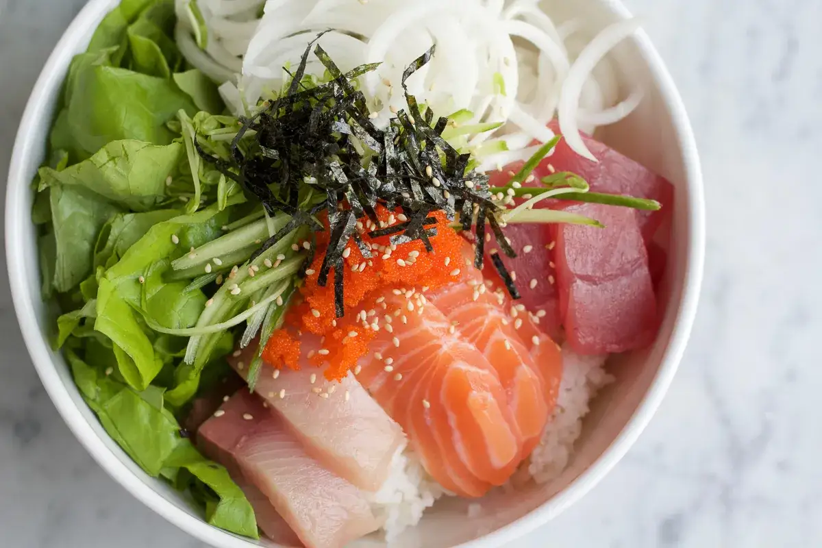En skål med ris, lax, tonfisk, grönsaker, rom och sjögräs. En vacker presentation som visar vad betyder sushi för många – färskhet och smak.