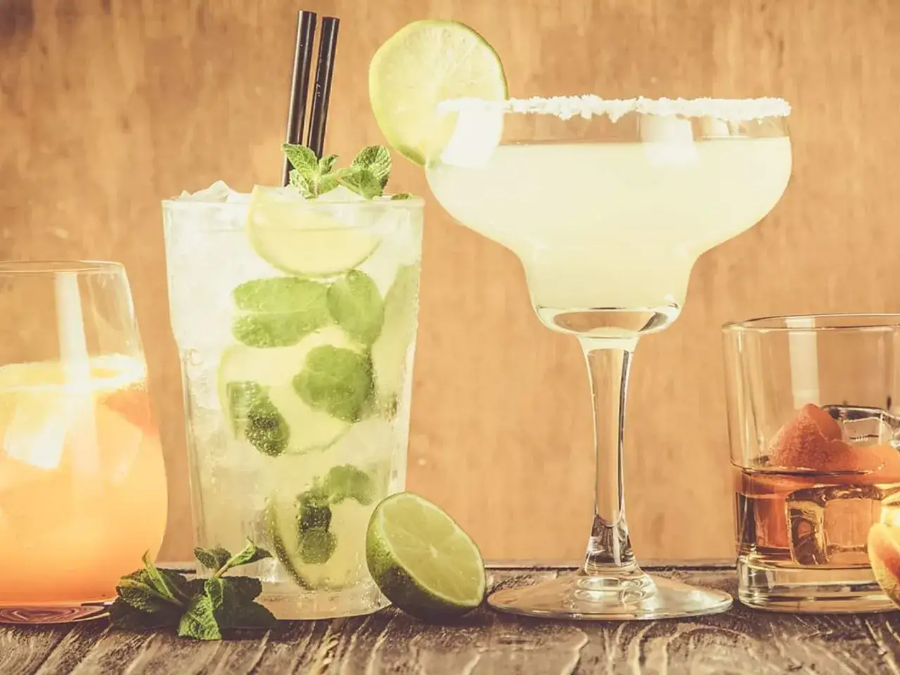 Fyra klassiska drinkar: en mojito, en margarita, en drink med apelsin och en whisky.