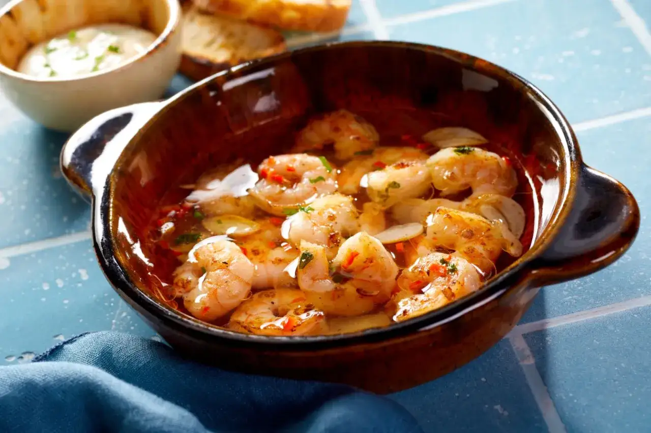 En sk&aring;l med saftiga gambas pil pil, full av vitl&ouml;k och chili, redo att avnjutas med rostat br&ouml;d.
