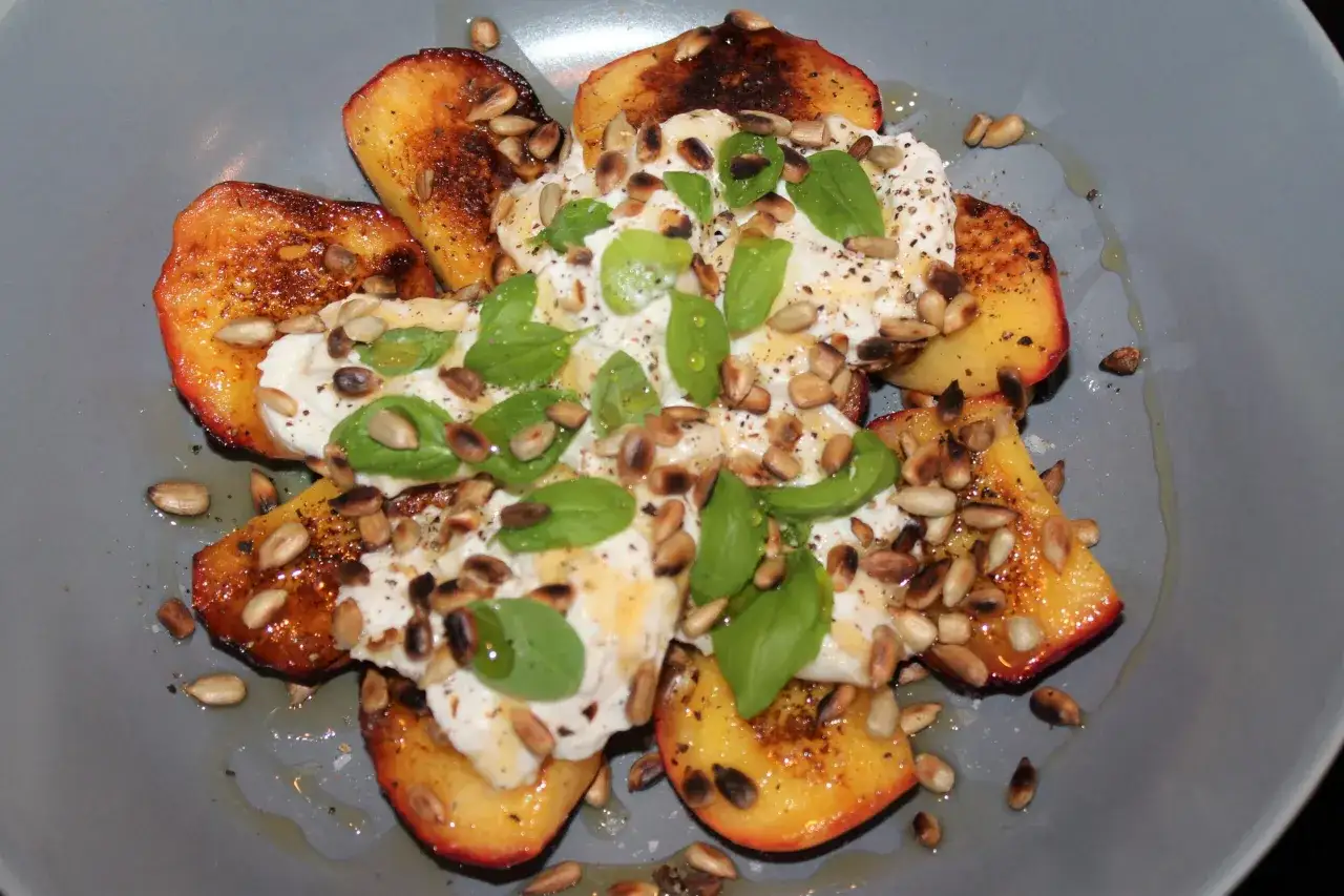 Grillad persika burrata med solrosfr&ouml;n och basilika. En somrig r&auml;tt som &auml;r perfekt som f&ouml;rr&auml;tt eller l&auml;tt lunch.