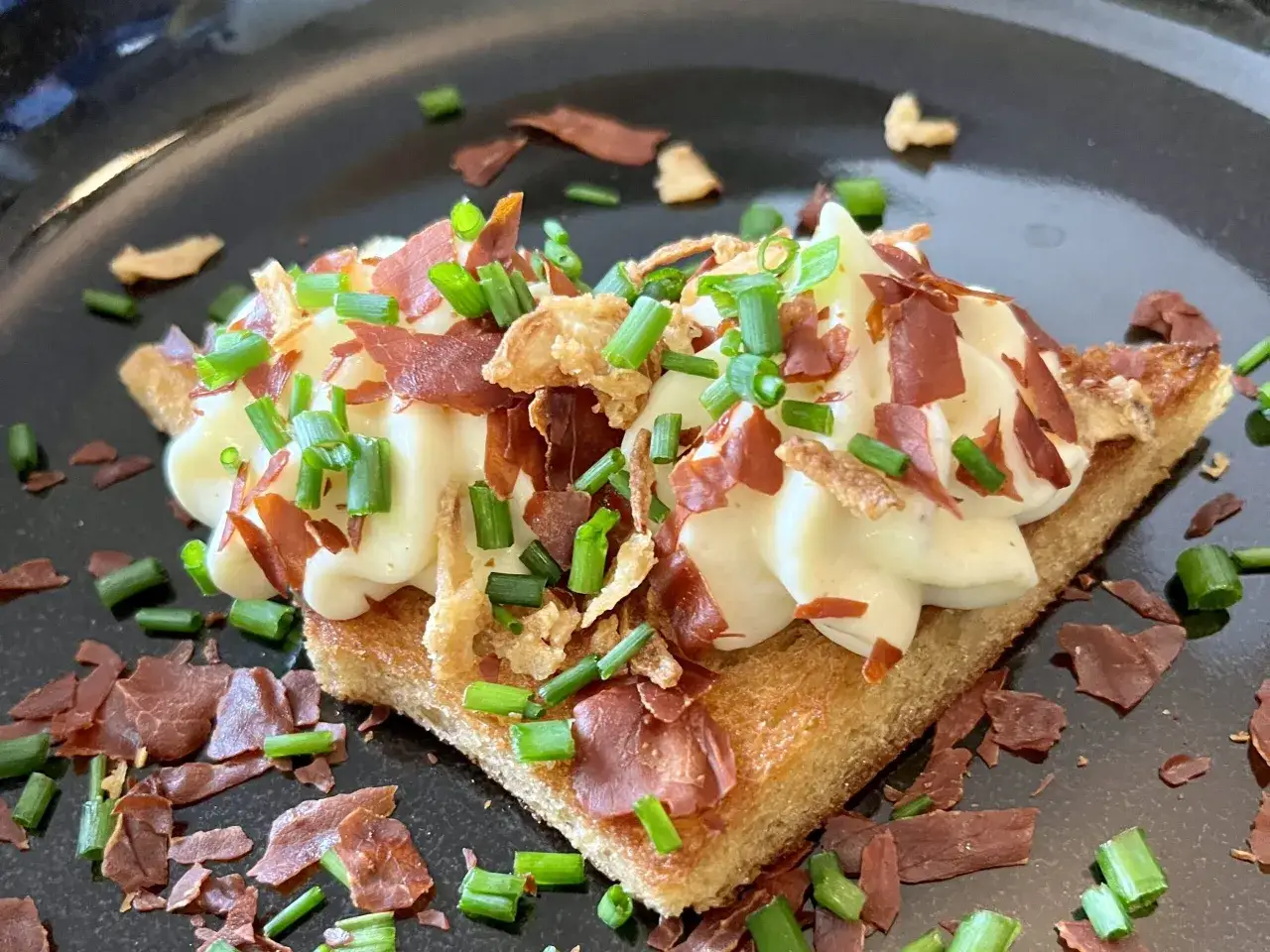 En rostad br&ouml;dskiva toppad med vispad brie, krispigt bacon och gr&auml;sl&ouml;k. En l&auml;cker liten munsbit!