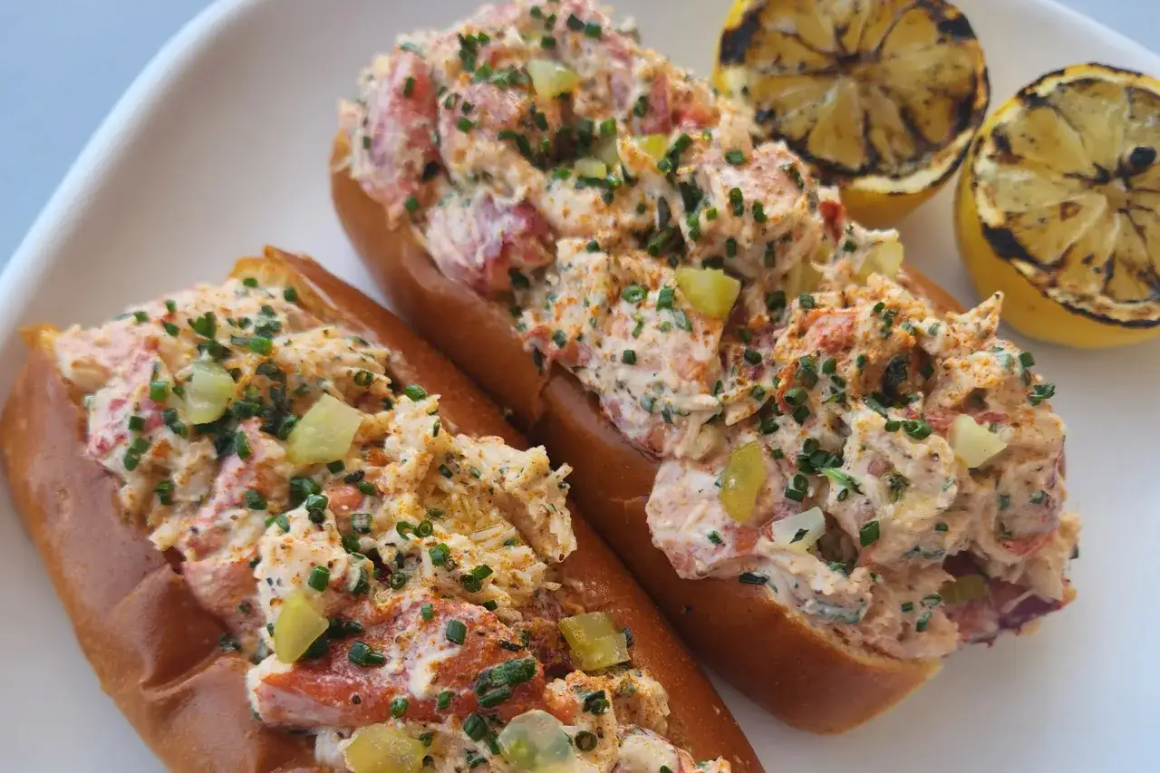 Tv&aring; lyxiga lobster rolls med kr&auml;mig fyllning, toppade med gr&auml;sl&ouml;k och serverade med grillade citronklyftor. Perfekt f&ouml;r ett somrigt lobster roll recept.