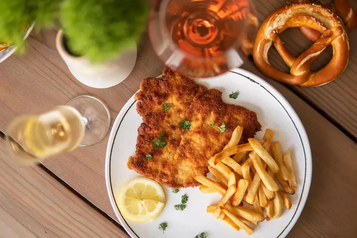 En krispig schnitzel med pommes frites, citron och ett glas vin. Perfekt för en härlig middag.