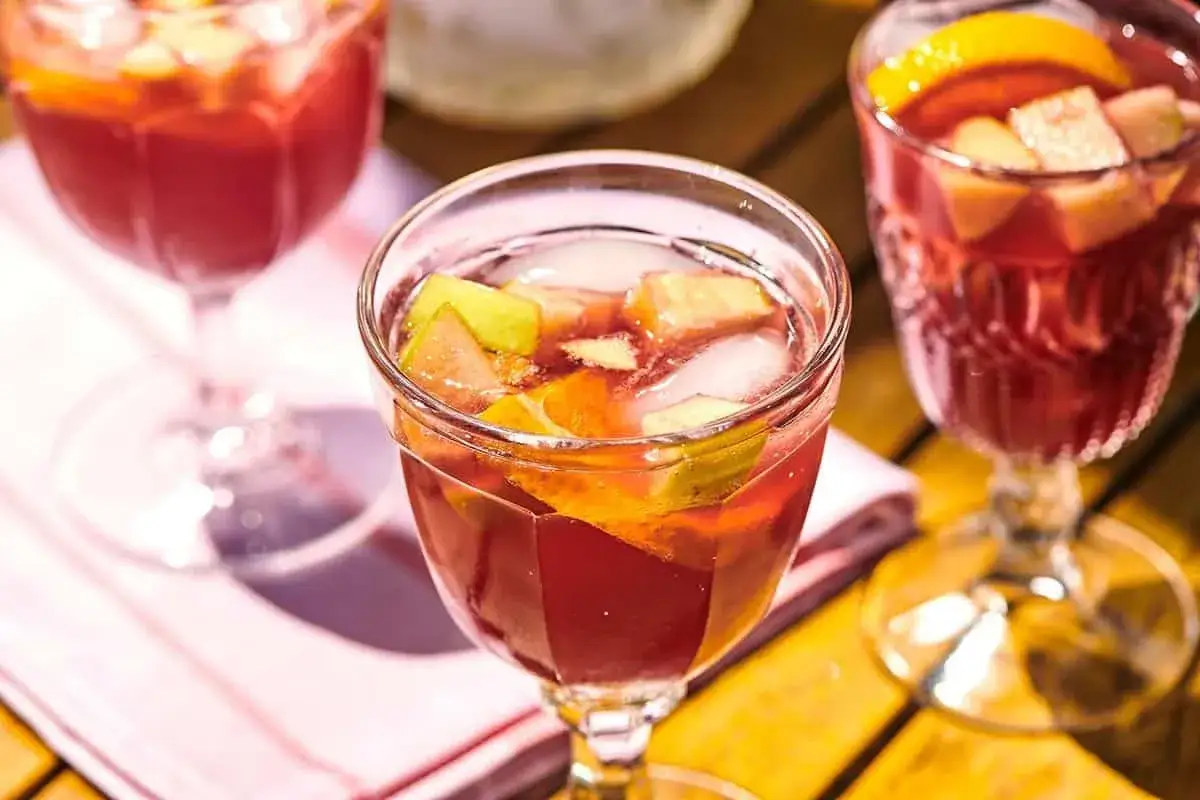 Tre glas med r&ouml;d sangria fyllda med frukt och is. Perfekt f&ouml;r ett enkelt sangria recept en solig dag.