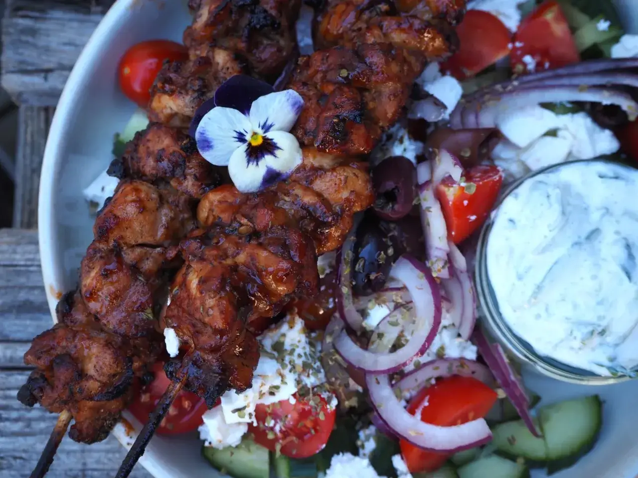 Grillad kyckling på spett, serverad med en fräsch sallad av tomat, gurka, rödlök, fetaost och oliver. Ett perfekt souvlaki recept för en somrig middag.