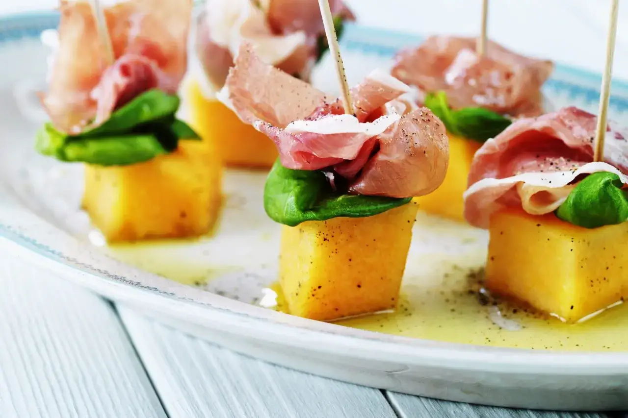 Sm&aring; t&auml;rningar av melon och skinka, toppade med basilika, serveras p&aring; ett fat med olivolja och peppar. En klassisk och l&auml;cker kombination!