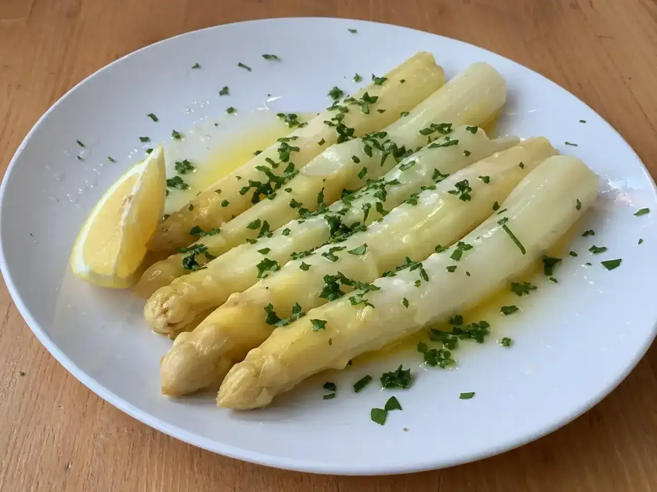 En tallrik med vit sparris, smält smör, citron och hackad persilja. En klassisk och utsökt rätt.