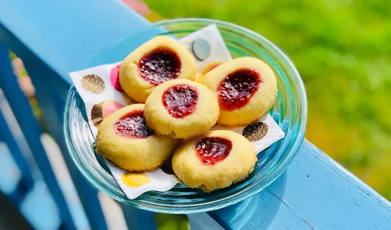 Fem enkla kakor med sylt i mitten, serverade på en blå träyta.