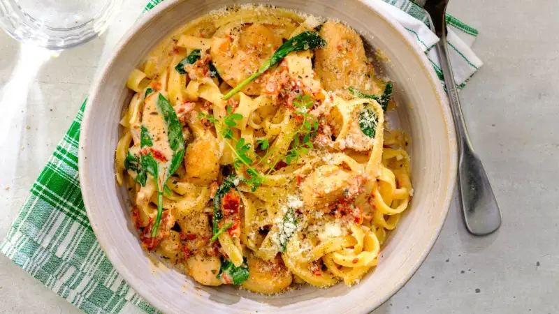 En krämig pastarätt med kyckling och soltorkade tomater, toppad med parmesan och färska örter.
