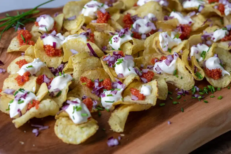 Krispiga chips med klickar av smetana, röd rom, finhackad rödlök och gräslök. En festlig förrätt!